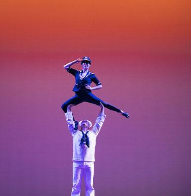 Two performers from SHOW Circus Studio in Easthampton, Massachusetts, one in a sailor suit, supporting overhead the other in a captain's outfit