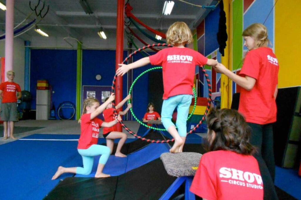 Kids holding hoops for another kid to walk through on a wire at SHOW Circus Studio in Easthampton, Massachusetts