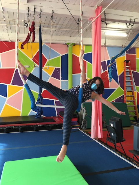 A kid sitting and kicking on a trapeze at SHOW Circus Studio in Easthampton, Massachusetts.
