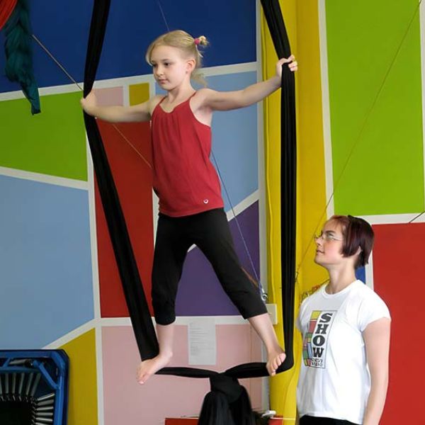 Spotter watching a child standing in a looped fabric trapeze at SHOW Circus Studio in Easthampton, Massachusetts